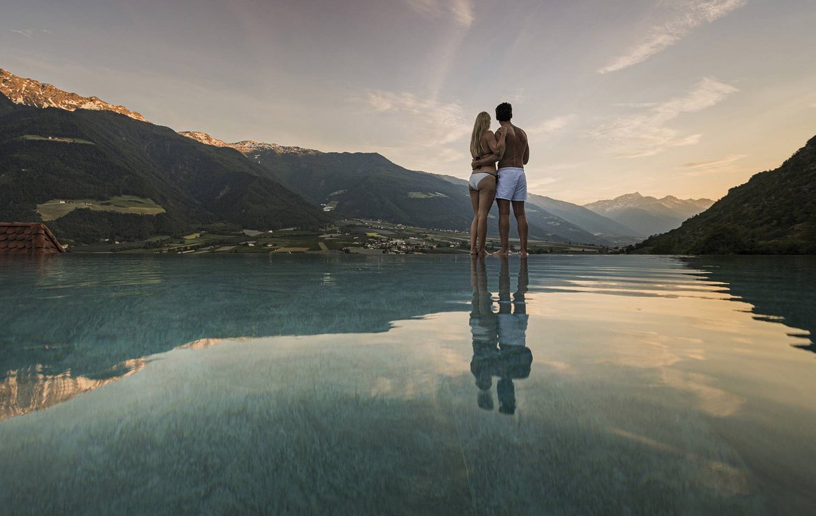 Ein Mann und eine Frau stehen am Rand eines Pools mit Blick auf die Landschaft